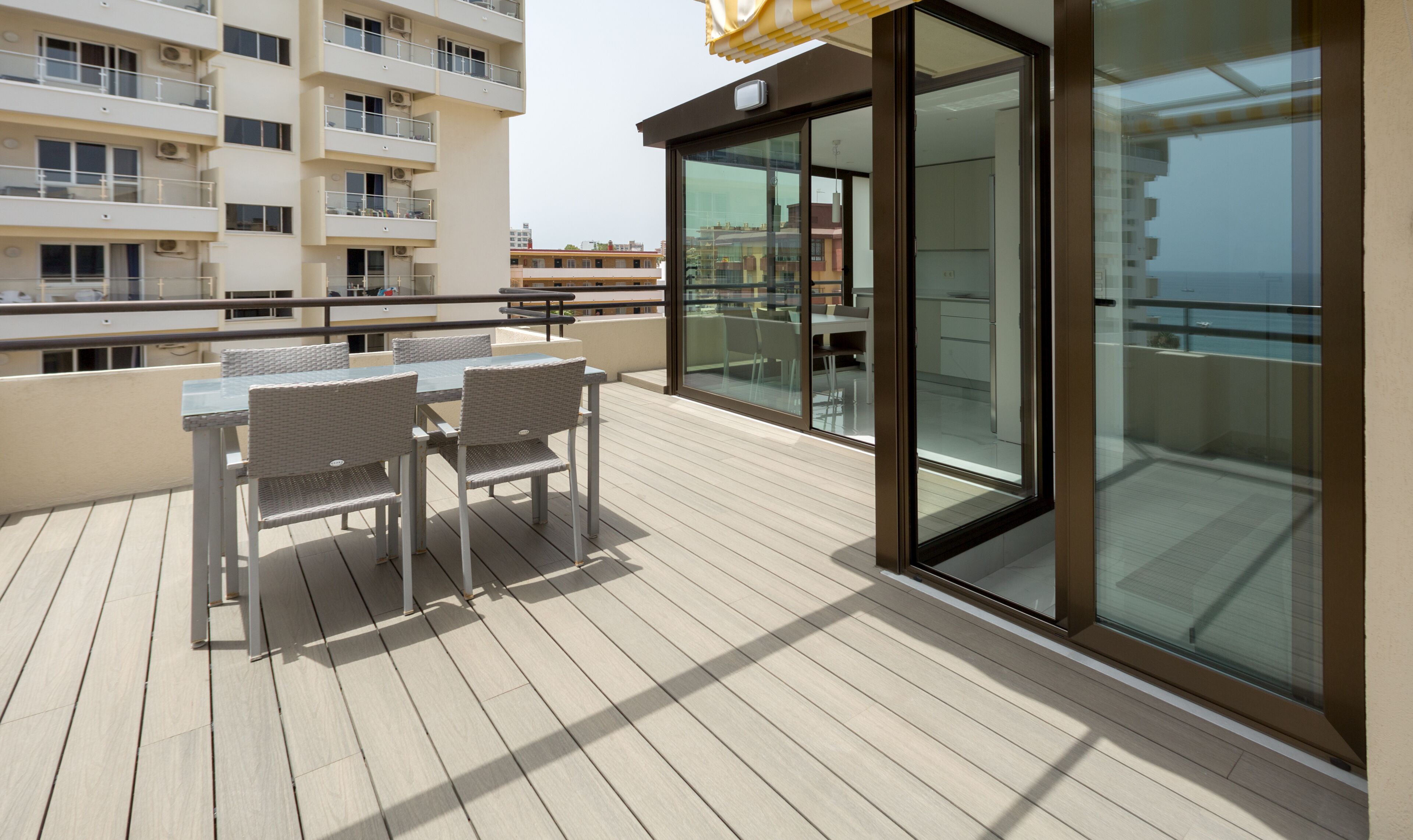 A balcony with a table and chairs, overlooking a cityscape.