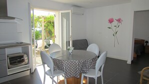 Una cocina con horno empotrado, una mesa de comedor con sillas blancas y vistas al exterior a través de un ventanal.