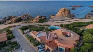 A coastal property with a swimming pool, terraced roofs, and rocky outcrops. - Villa Sfumature del Melograno: private pool in front of the sea (Costa Paradiso)
