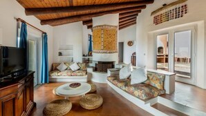 A cozy living room with a fireplace, sofas, and a television. - Villa Sfumature del Melograno: private pool in front of the sea (Costa Paradiso)