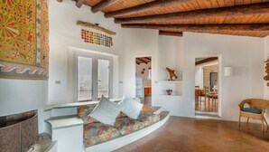 A spacious living area with a curved sofa, a fireplace, and a view of the outdoors. - Villa Sfumature del Melograno: private pool in front of the sea (Costa Paradiso)