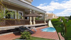 A poolside area with lounge chairs, a small pool, and a wooden deck.