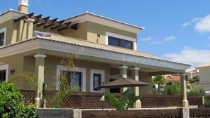 A two-story house with a covered patio area, a chimney, and a pergola.