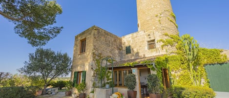 A stone building with a tower, potted plants, and a clear sky.