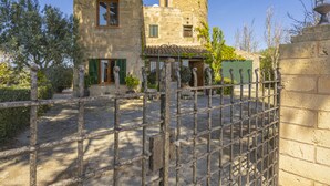 Un bâtiment en pierre doté d’une tour, d’une porte et d’une cour dallée.