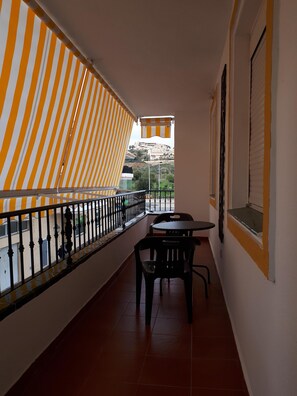 Enjoy the hillside view from this balcony with a striped awning and seating for two.