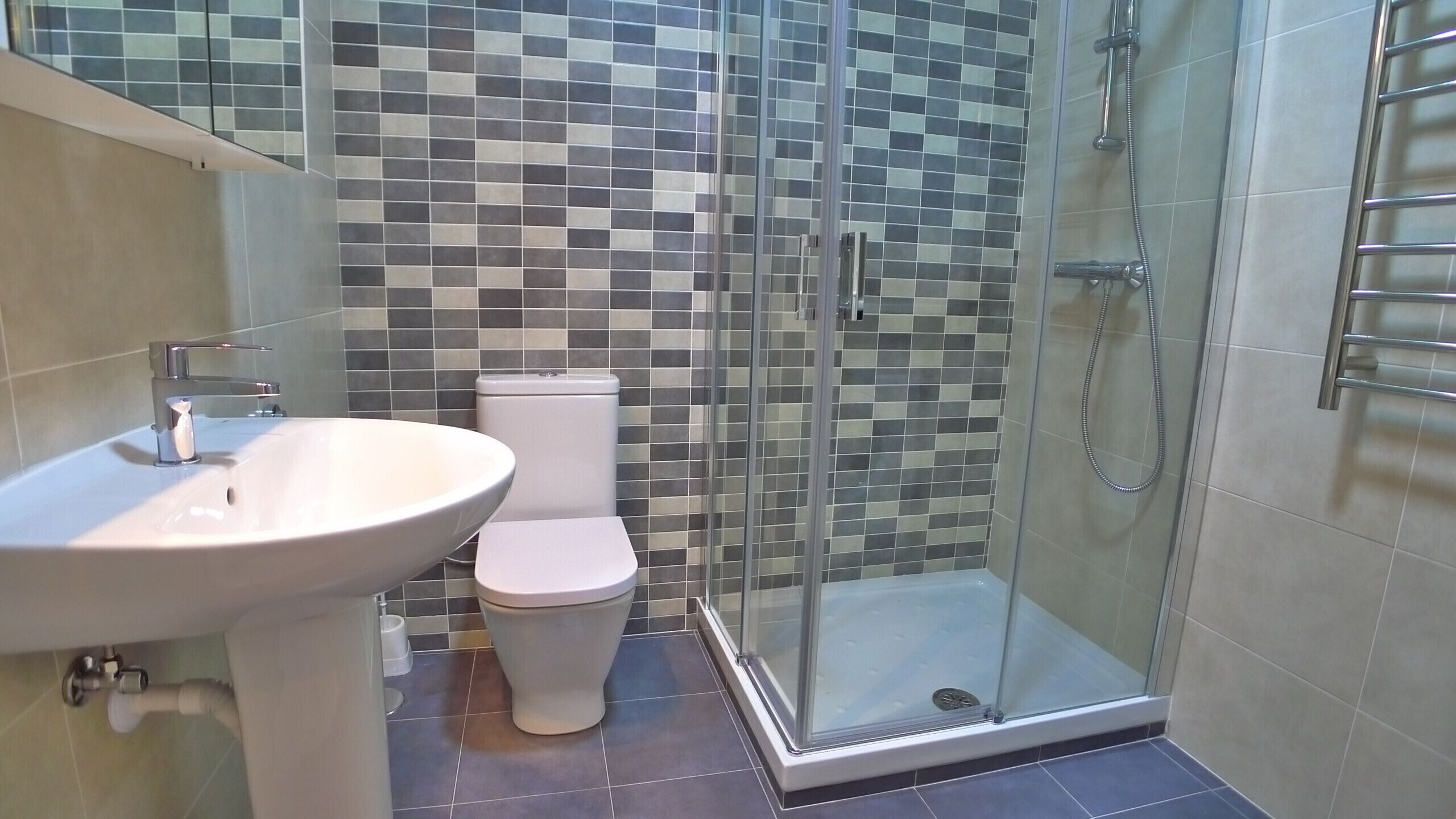 Une salle de bain avec une douche à parois de verre, un lavabo blanc et des toilettes.