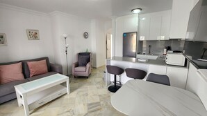 A modern living room with a sofa, a coffee table, and a dining area with a bar. - Stella Maris | CG R908 (Nerja)