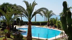 A pool surrounded by palm trees and cacti, with a view of the ocean. - Stella Maris | CG R908 (Nerja)