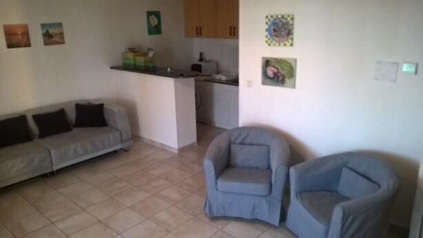 A living room with a sofa and two armchairs, a kitchen area with cabinets, and a small island. - Beachside sea views, aircon, internet, modern, private parking (Mèze)