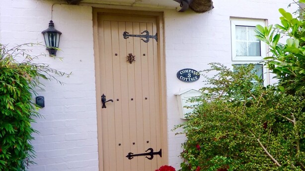 A traditional cottage with a thatched roof, a wooden door with a brass handle, and a sign reading "Compass 3 Cottage". - Pretty Thatched Cottage, close to sandy beach (winterton on sea)