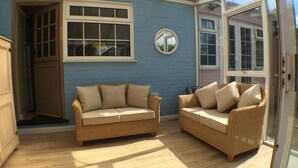 A room with two wicker sofas, a blue wall, and a large window. - Pretty Thatched Cottage, close to sandy beach (winterton on sea)