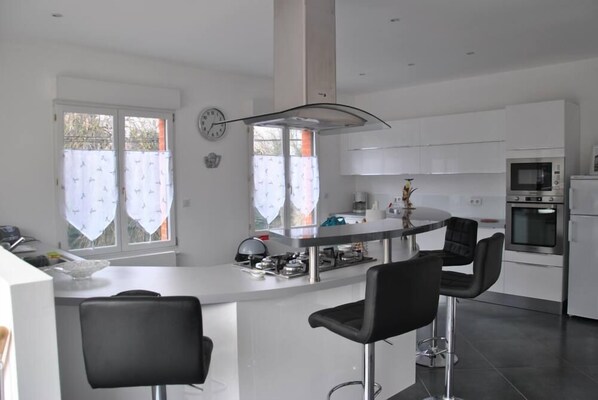 A modern kitchen with a central island, bar stools, and stainless steel appliances. - ARRAS BEAUTIFUL HOUSE, LARGE TERRACE WITH VIEW ON VERY NICE PARK (Arras)