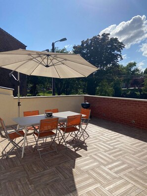 An outdoor patio with a table and chairs, a large umbrella, and a brick wall. - ARRAS BEAUTIFUL HOUSE, LARGE TERRACE WITH VIEW ON VERY NICE PARK (Arras)