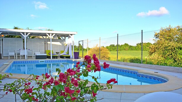 Une piscine dotée d’un espace de repos couvert et d’une pergola.