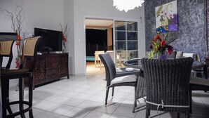 Un coin repas avec des chaises en osier, une table à plateau en verre et un vase décoratif.