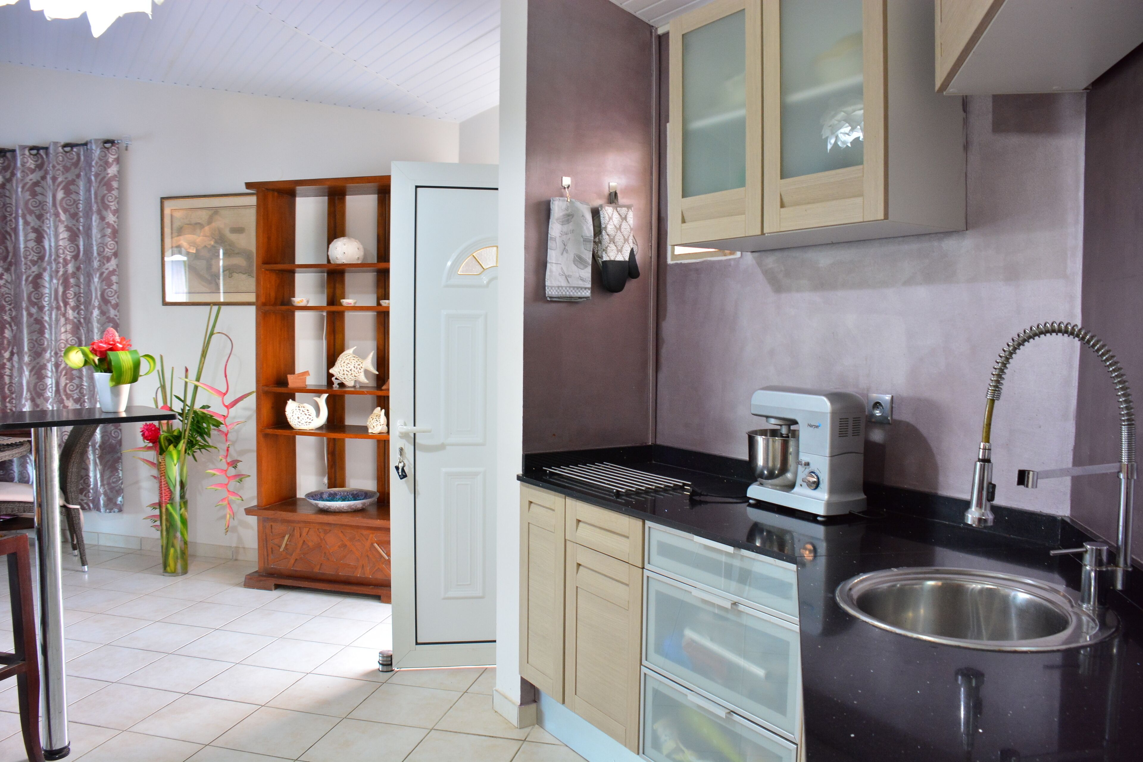 A modern kitchen with a black countertop, stainless steel sink, and wooden cabinets.