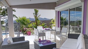 Un espace extérieur abrité, aménagé avec des meubles en osier, une table et des chaises.