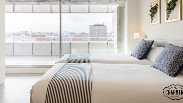 Ein modernes Hotelzimmer mit zwei Betten, großen Fenstern und Blick auf die Stadt.