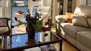 A living room with a glass coffee table, a sofa, a chair, and a bookshelf.