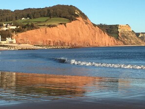 Un paisaje costero con una playa arenosa, un acantilado y una masa de agua.