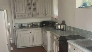 A kitchen with white cabinets, a tiled backsplash, and a tiled floor. - Contemporary Beach House with sea views and short walk to Blue Flag beach (Porthtowan)