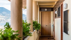 A corridor with wooden columns, a wooden door at the end, and a view of a cityscape and mountains in the distance. - Comfortable, contemporary and tranquil flat with sea views in the centre of town (Fuengirola)