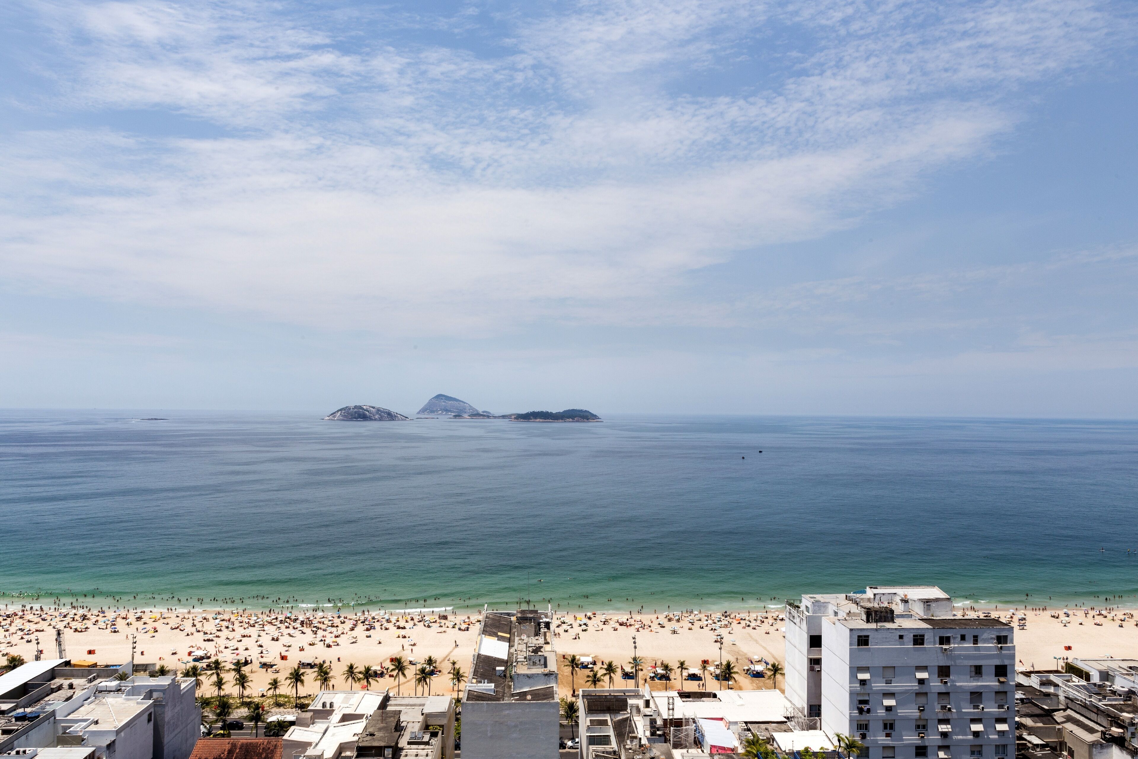 Paisagem costeira com praia, edifícios e céu claro.