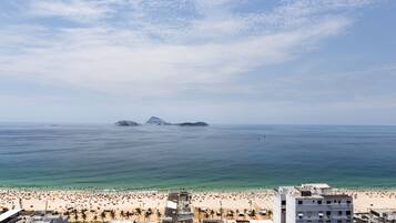 Paisagem costeira com praia, edifícios e céu claro.