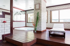 A spa area with a wooden deck, a hot tub, a massage table, and a vase with flowers. - Heart of Ipanema, stylish apartment in full service building. IDEAL LOCATION! (Rio de Janeiro)