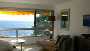 A room with a large window overlooking the sea, a sofa, a small round table, and a TV. - Apartment/ flat - Bandol,  Sea front, A/C, private parking place (Bandol)