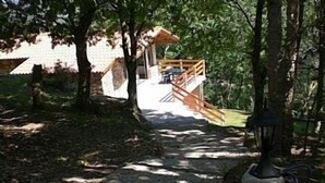 Ein Weg, der zu einer Holzterrasse mit einem Gazebo führt, umgeben von Bäumen.