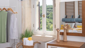 A bathroom with a wooden vanity, a wicker basket with towels, a potted plant, and a window with a view of greenery. - Dafni Villa, a Blissful Retreat with 40m² Pool (Rethymno)