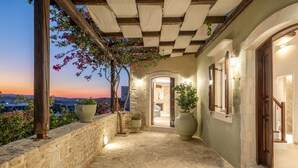 A stone-paved pathway leading to a building with a wooden pergola and potted plants. - Dafni Villa, a Blissful Retreat with 40m² Pool (Rethymno)