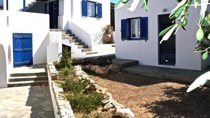 Un edificio blanco con contraventanas azules y una escalera de piedra que conduce a una puerta.