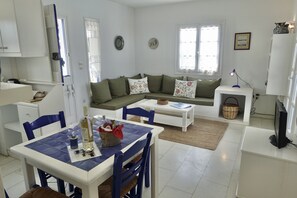 A modern living room with a sofa, a dining table, and a TV.