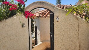 Un arco in pietra con un cartello con il numero '9', che conduce a un edificio con tegole in terracotta.