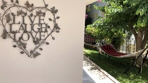 Een decoratief metalen bord met de woorden 'LIVE LAUGH LOVE', omringd door bladeren en vlinders.