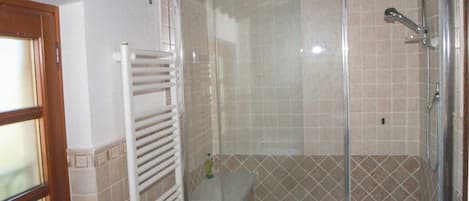 A bathroom with a glass-enclosed shower, a white bathtub, and a towel rack.