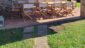 Un bâtiment en pierre doté d’un patio comprenant une table et des chaises en bois.