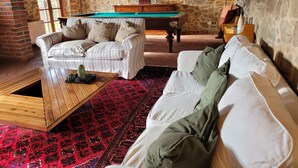 Une pièce chaleureuse avec une table de billard, un canapé et un tapis à motifs.