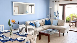 A modern living room with a dining area, a sofa set, and a large mirror.