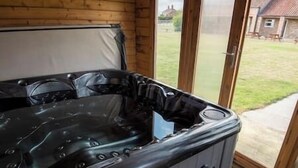 Un jacuzzi con panel de control, una pared de madera y una puerta de cristal que da a un área exterior.