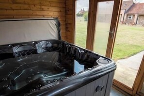 Un bain à remous doté d’un panneau de commande, d’un mur en bois et d’une porte en verre donnant sur un espace extérieur.