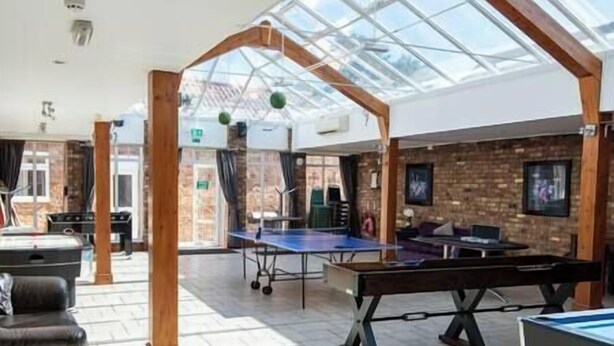 Un área recreativa interior con mesa de ping pong, mesa de billar y mesa de futbolín.
