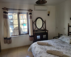 Une chambre à coucher avec un lit, une commode, un miroir et une fenêtre avec des rideaux.