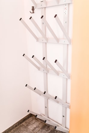 Un étagère métallique blanche, fixée au mur et dotée de plusieurs crochets.