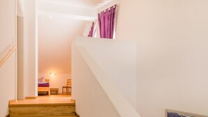A staircase leading to a bedroom with a bed, a chair, and a small table. - Chalet Vergissmeinnicht, spacious property in Zell am See, includes Summer Card (Zell am See)