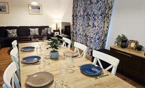 A dining area with a wooden table set for four, surrounded by white chairs. - Chalet Vergissmeinnicht, spacious property in Zell am See, includes Summer Card (Zell am See)