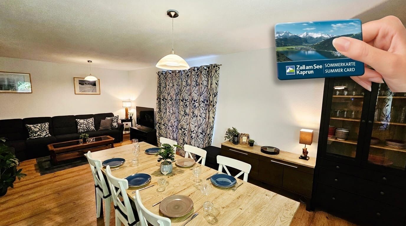 Een eetruimte met een houten tafel voor vier personen, witte stoelen en uitzicht op een berglandschap door een raam.